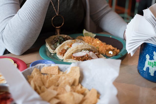 Person Sitting in Front of Tacos on Plate