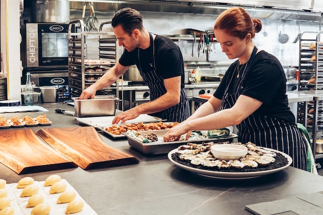 two-cooks-in-restaurant-kitchen-preparing-sushi-on-cutting-boards